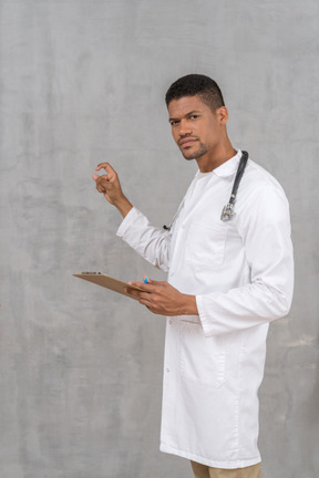 Young doctor with stethoscope holding clipboard