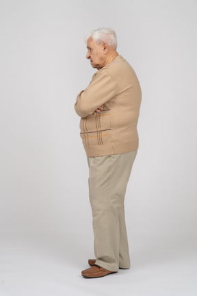 Vue latérale d'un vieil homme en vêtements décontractés debout avec les bras croisés