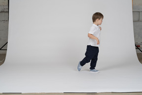 Vista lateral de un niño dando un paso a la derecha