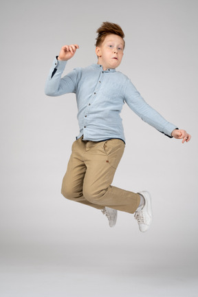 A boy in white sneakers jumping with bent knees