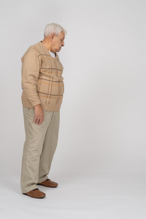 Вид сбоку на старика в повседневной одежде, смотрящего вниз