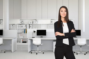 A business woman standing in an office with her arms crossed