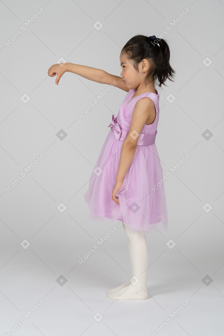 Vista lateral de uma menina dando polegares para baixo