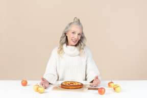 Vieille femme élégante offrant à essayer sa tarte aux pommes fraîchement cuite