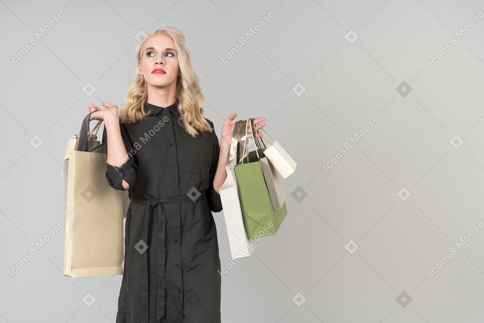 A young beautiful blond-haired person in a black dress holding a bunch of shopping bags in both of their hands