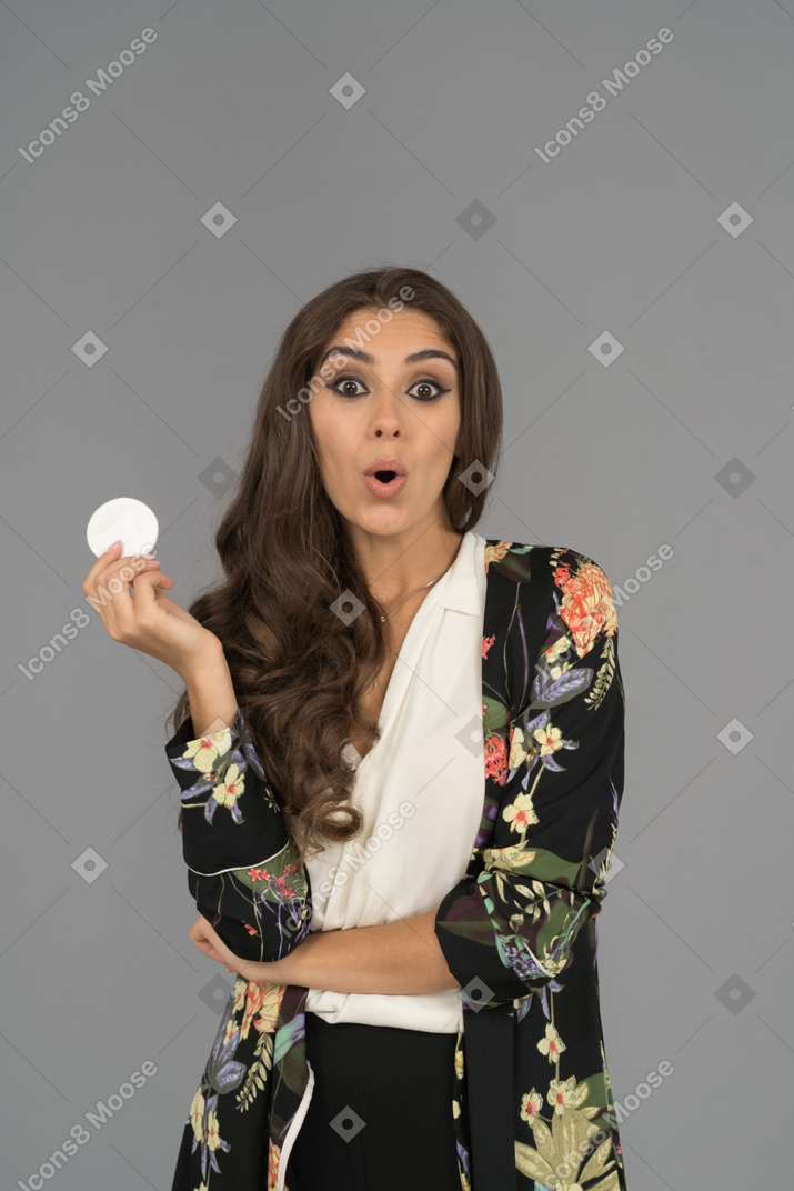 Mujer del medio oriente sorprendida sosteniendo una almohadilla de algodón