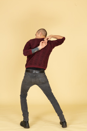 Back view of a young man in red pullover stretching his arms