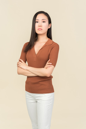 Serious looking young asian woman standing with hands crossed