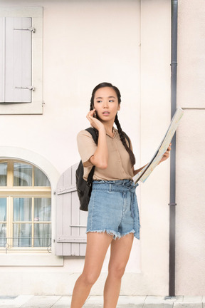 A woman standing in front of a building talking on a cell phone