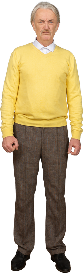 Vorderansicht eines wütenden alten mannes, der kamera betrachtet und einen gelben pullover trägt