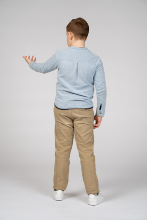 Back view of a boy standing with extended arm