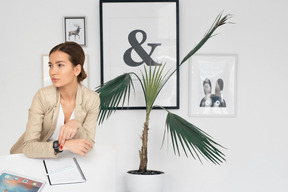 A woman sitting at a desk next to a plant