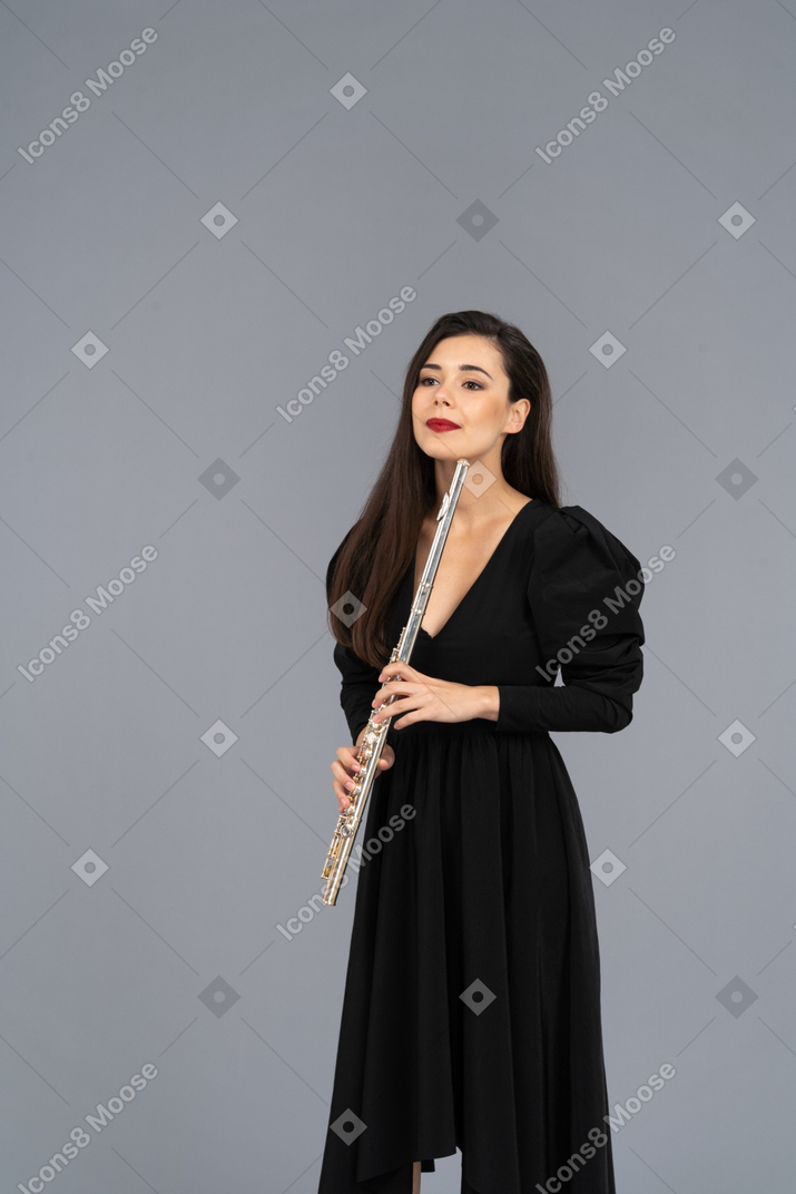 Vorderansicht einer jungen dame im schwarzen kleid, das flöte hält