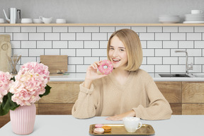 A woman sitting at a table eating a doughnut
