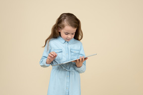 Милая маленькая девочка с помощью планшета