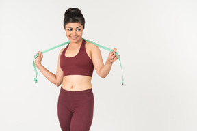 Young indian woman in sporstwear standing with cloth ruler on her neck
