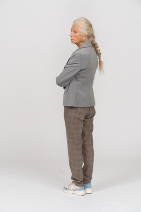 Vista posteriore di una vecchia donna in tuta in posa con le braccia incrociate