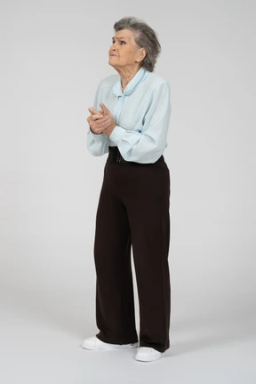 Front view of an old woman clasping hands anxiously