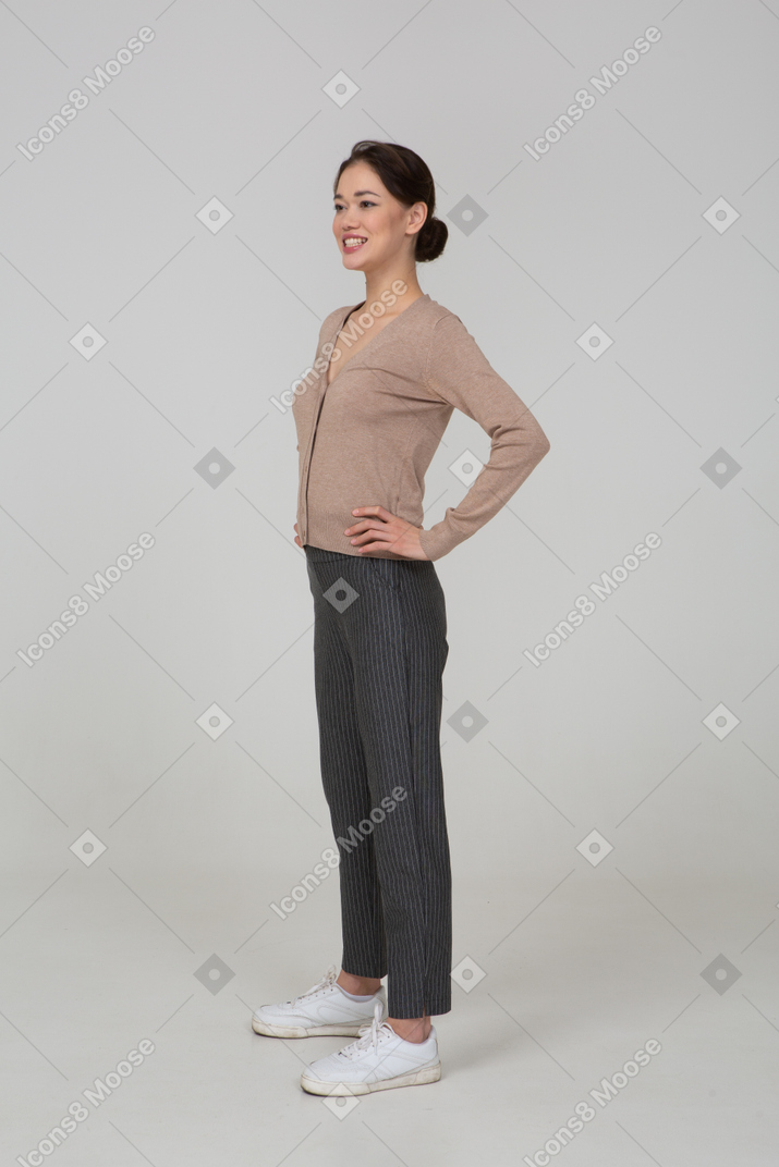 四分之三的微笑的女性，在套头衫和裤子放在臀部上的裤子