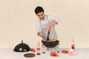 Junger kaukasischer mann konzentrierte sich auf das kochen des grills