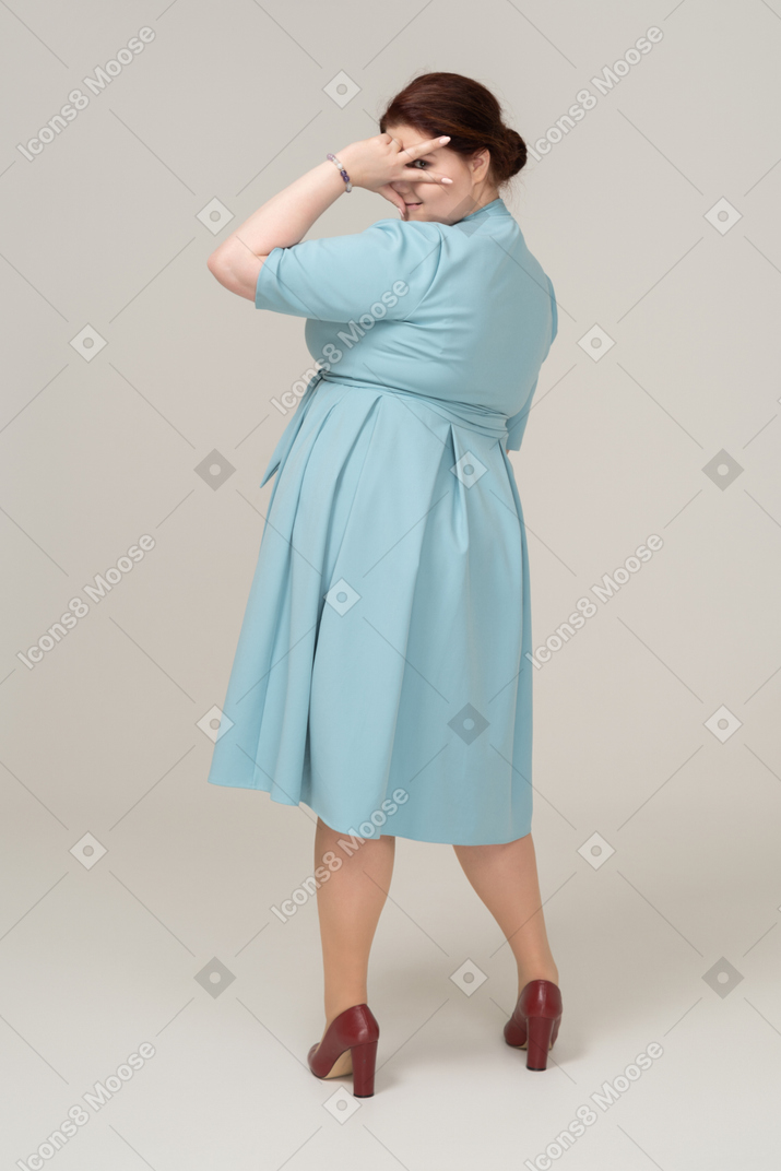 V記号を示す青いドレスを着た女性の側面図