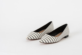A three-quarter front shot of a pair of a pair of striped flat black and white shoes