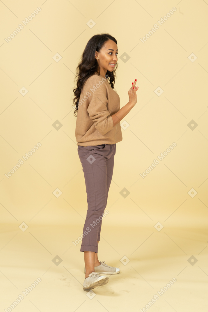 Three-quarter view of a cheerful dark-skinned young female showing ok sign