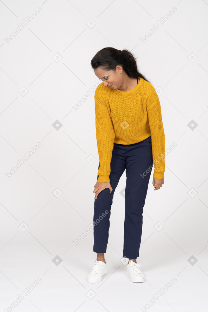 Front view of a girl in casual clothes touching her hurting knee