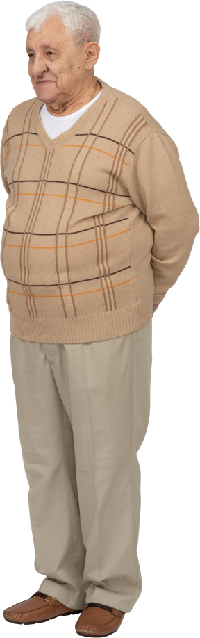 Вид спереди счастливого старика в повседневной одежде, стоящего с руками за спиной
