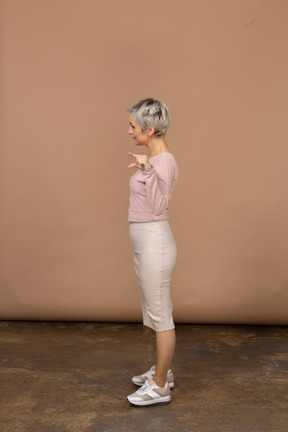 Side view of a happy woman in casual clothes showing the small size of something