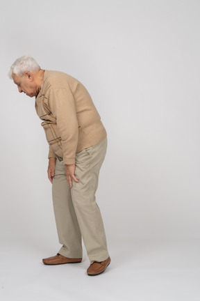 Vista lateral de un anciano con ropa informal agachándose