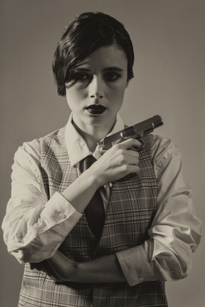 Close-up of a cheerless young woman with a gun