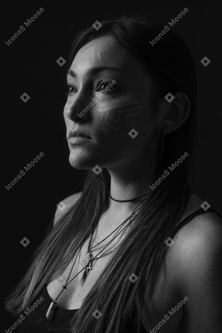 脇を向いているフェイスアートを持つ若い女性の側面図ノワール写真