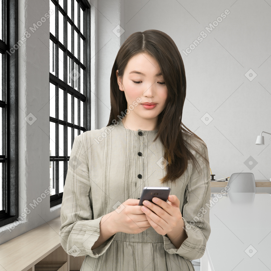 A woman standing in a room looking at a cell phone
