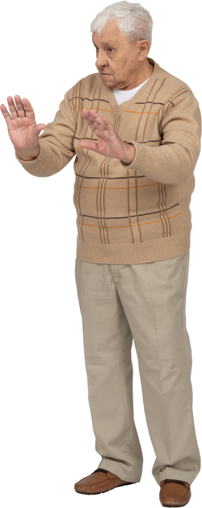 Front view of an old man in casual clothes showing stop gesture