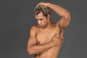Vista frontale di un uomo afro a torso nudo che si tocca la testa