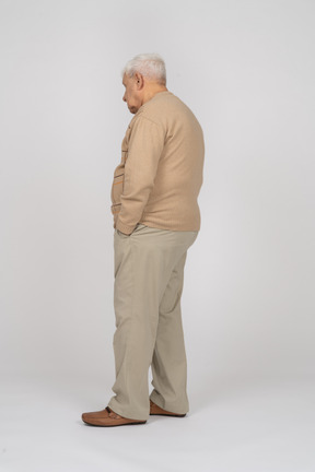 Vue latérale d'un vieil homme en vêtements décontractés debout avec les mains dans les poches