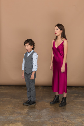 Sleepy woman in red dress and boy in grey suit vest