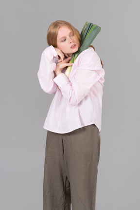 Young woman holding leek onion close to herself