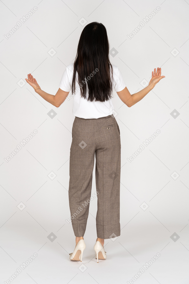 Vista traseira de uma jovem de calça, estendendo as mãos