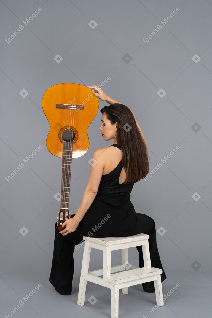 Young woman holding a guitar upside down