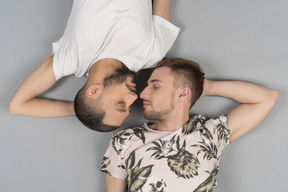 Flat lay of two young caucasian men lying symmetricly face to face looking at each other