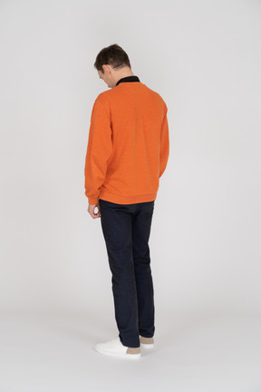 Young man in orange sweatshirt standing