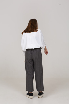 Back view of a young lady in office clothing pointing finger
