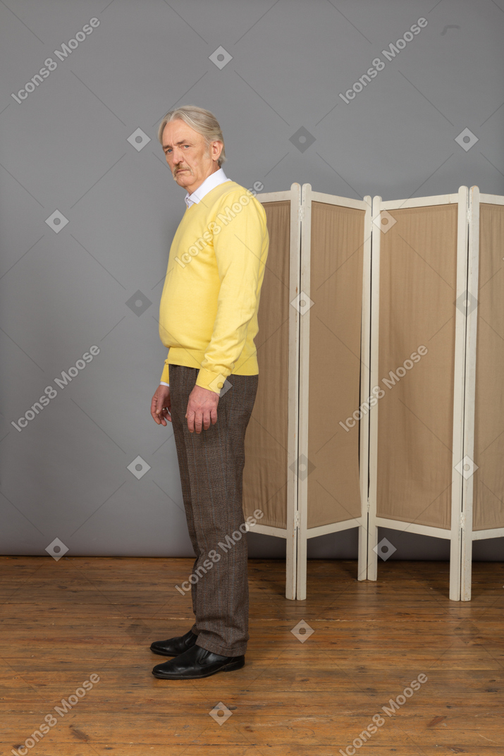 Side view of an old man standing still looking at camera