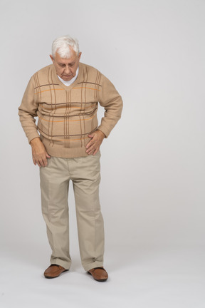 Vue de face d'un vieil homme pensif dans des vêtements décontractés regardant vers le bas