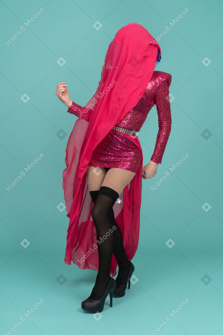 Drag queen in pink drace covering face with long skirt