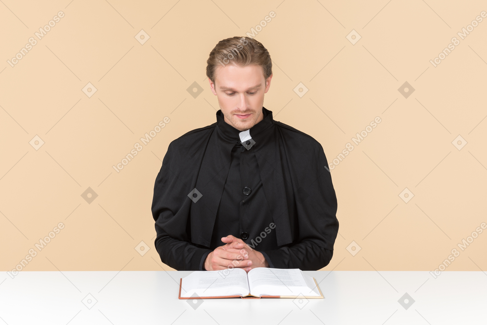 Catholic priest sitting at the table and reading a bible