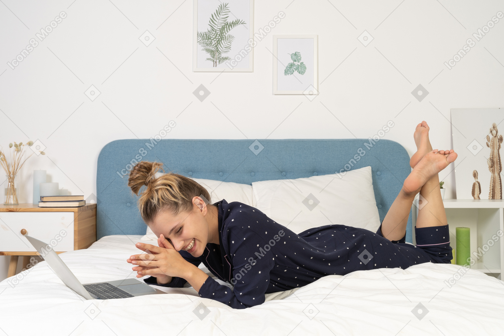 一个笑着的年轻女性躺在床上，带着她的笔记本电脑的侧视图