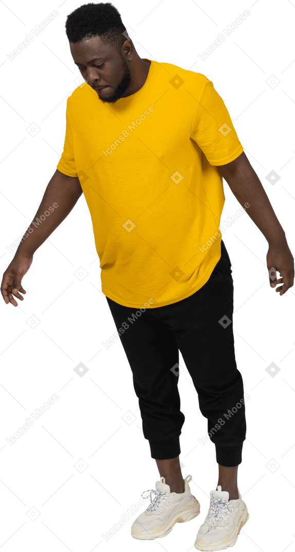 Вид в три четверти молодого темнокожего мужчины в желтой футболке, наклонившегося вперед и протягивающего руку